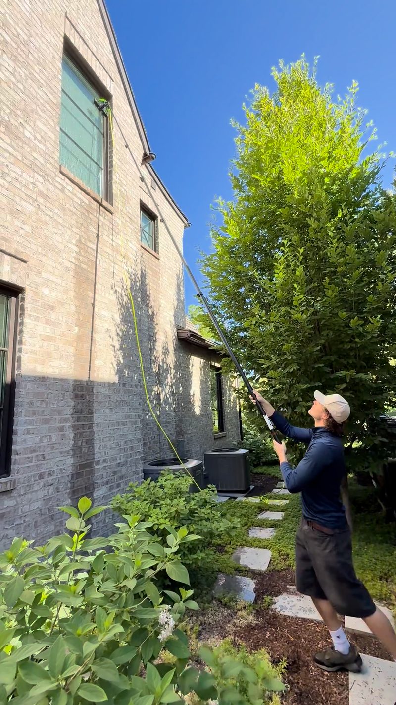 Professional window cleaning technician working on exterior windows with equipment